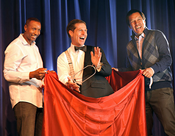 Peter Morrison on stage performing his magic with the help of two audience members
