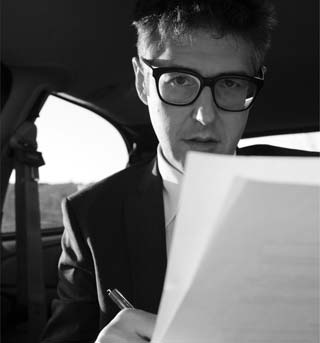 image of Ira Glass writing in the car - photo by NANCY UPDIKE